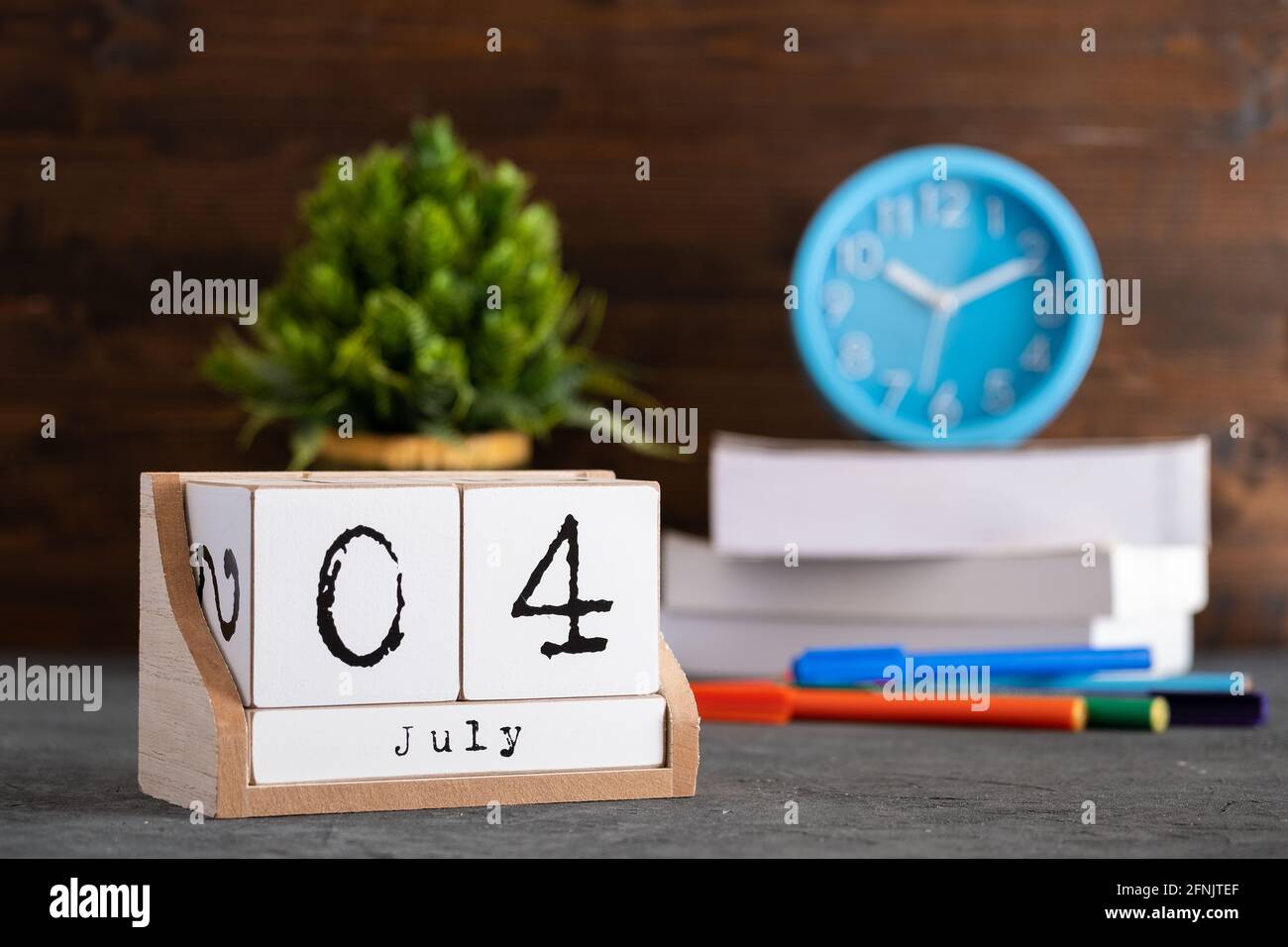 Juli. Juli 04 Holzwürfelkalender mit unscharfen Objekten auf dem Hintergrund. Stockfoto