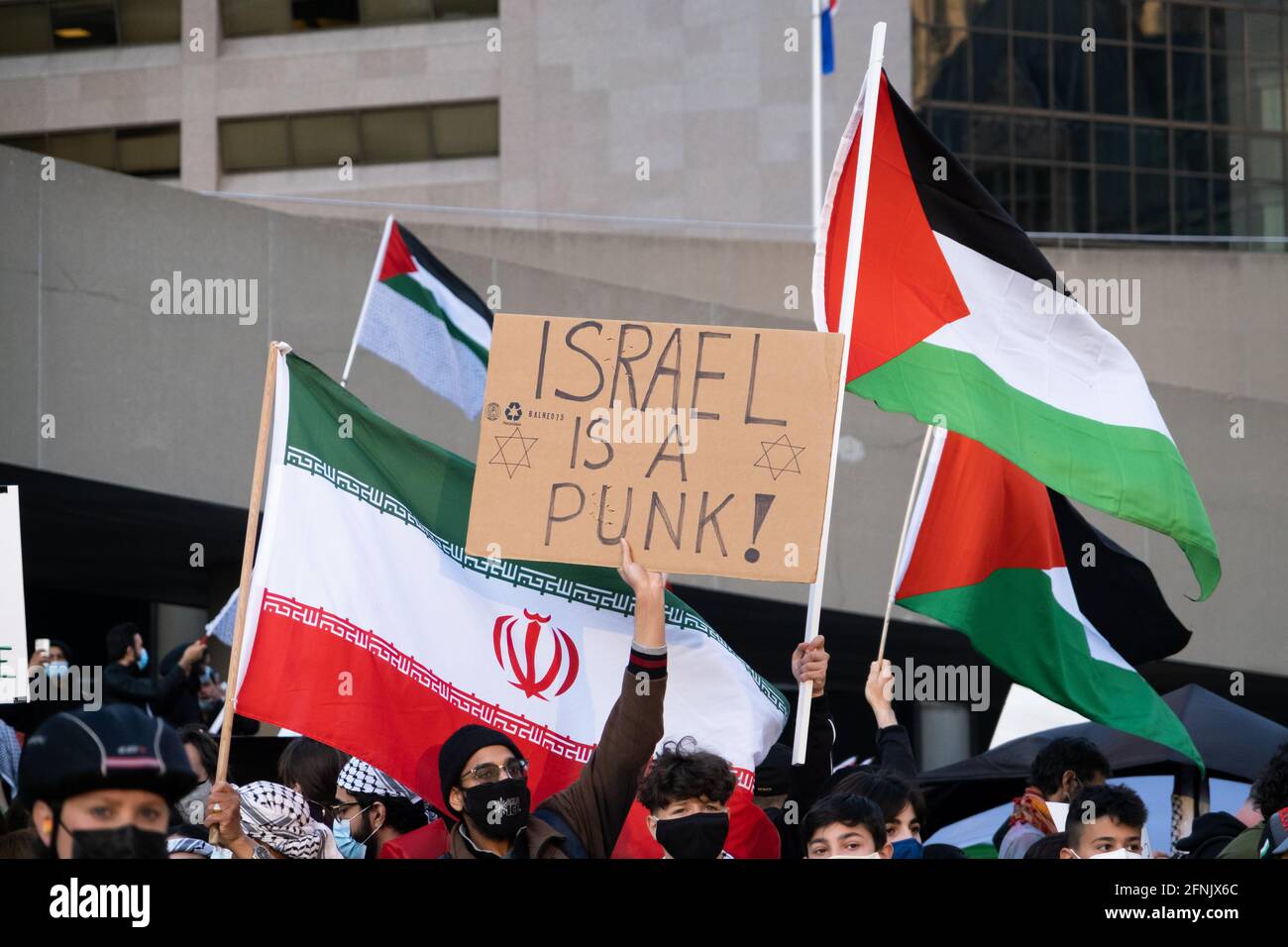 Pro-palästinensische Demonstranten verurteilen Israel, während sie bei einer anti-israelischen Veranstaltung in Toronto, Kanada, palästinensische und iranische Regime-Flaggen schwenken. Stockfoto