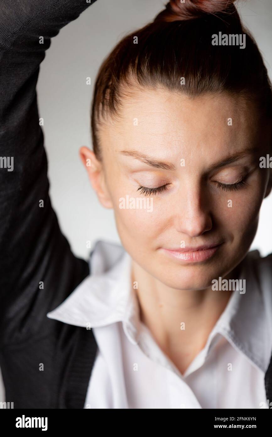 Eine junge Frau mit einem leichten Lächeln und geschlossenen Augen Trägt einen weißen shir Stockfoto