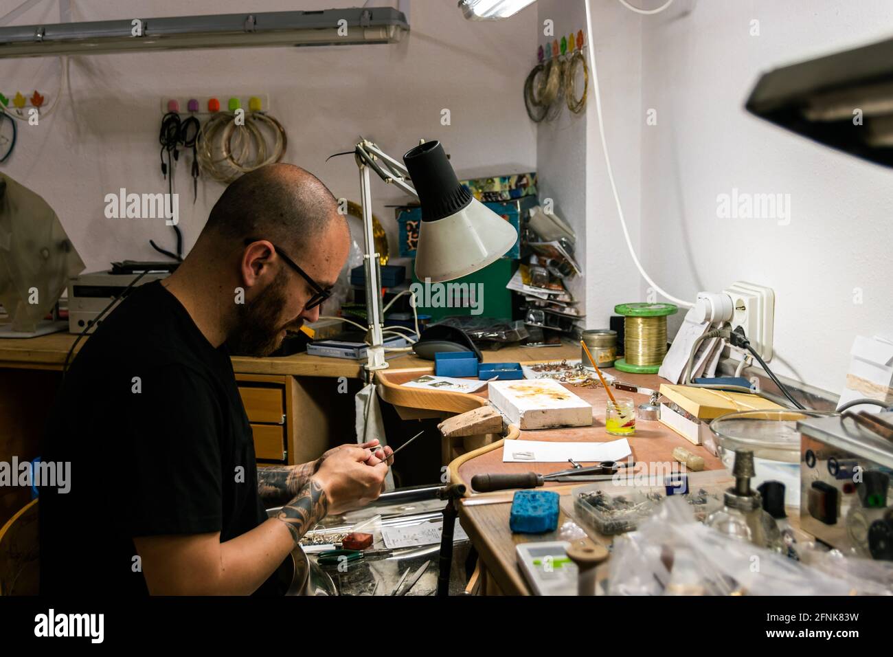 Mann in der Schmuckwerkstatt, der ein Stück Silber einreicht. Mittlere Aufnahme Stockfoto