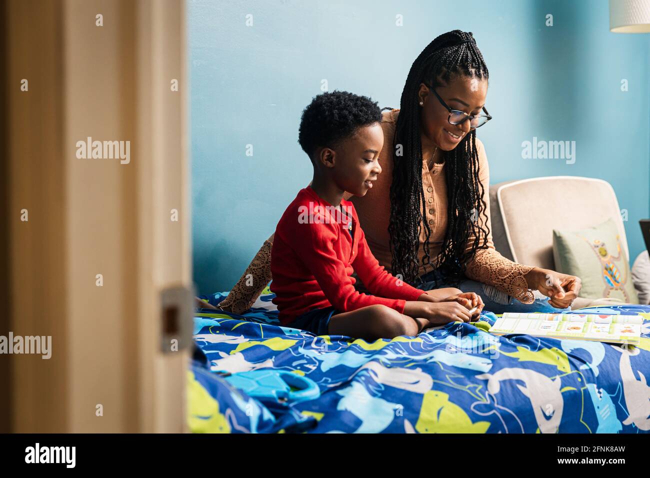 Mutter, die Sohn beim Studieren im Schlafzimmer zu Hause unterstützt Stockfoto