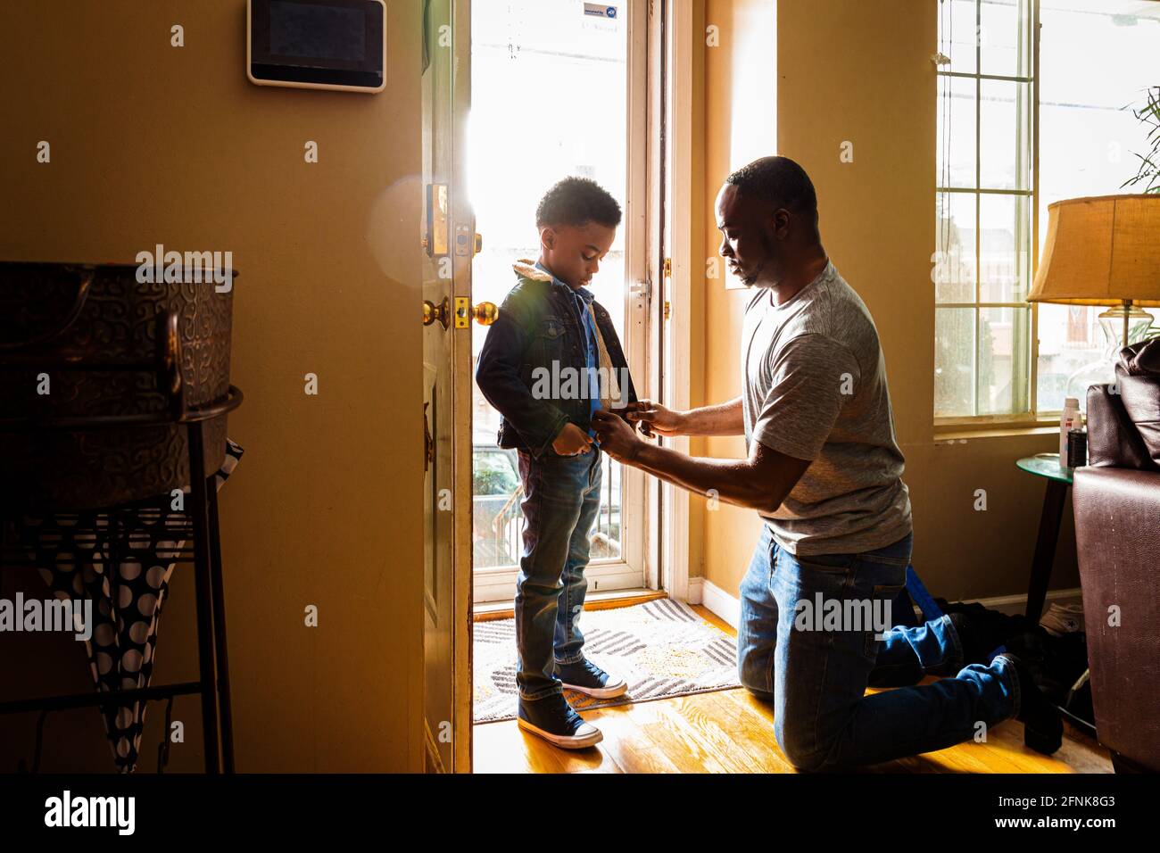 Vater hilft Sohn beim Anziehen am Eingang des Hauses Stockfoto