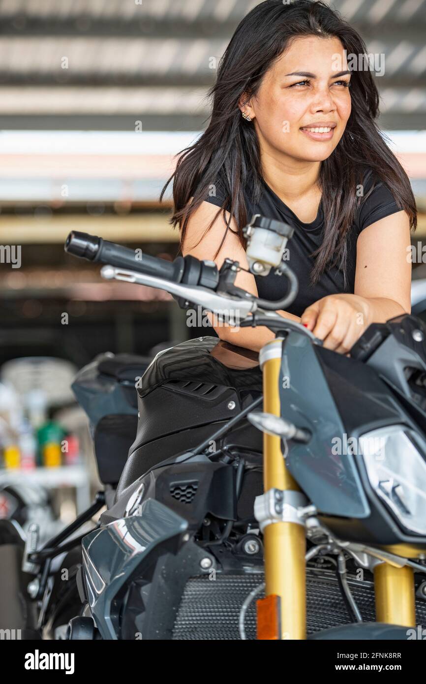Frau lehnte sich über ihr Motorrad und schaute auf die Rennstrecke In Bangkok Stockfoto
