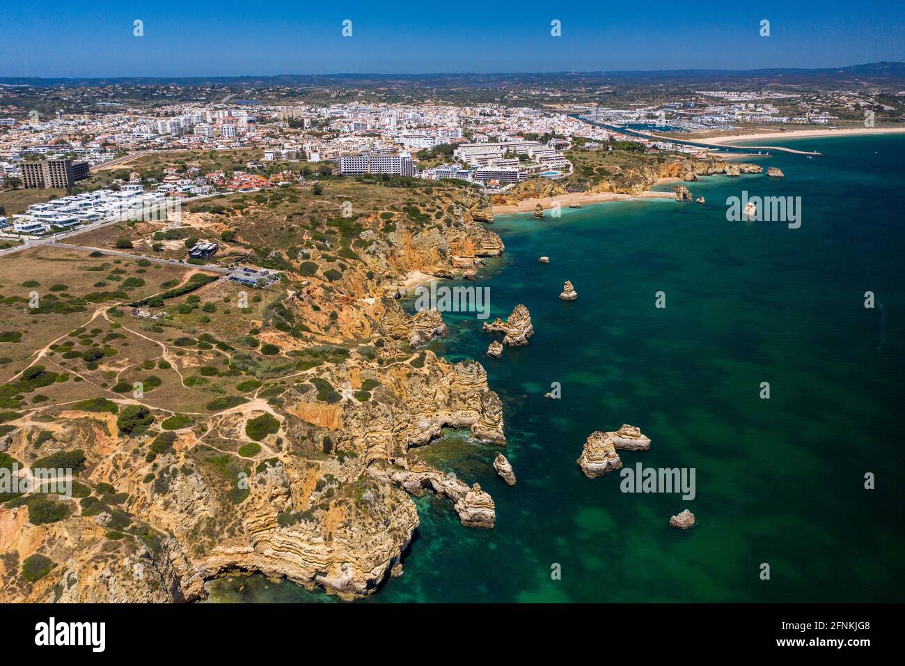 'Ponta da Piedade' - portugiesische goldene Küstenklippen im Süden. Luftaufnahme über die Stadt Lagos an der Algarve, Portugal. Im Hintergrund der Strand Meia praia. Stockfoto