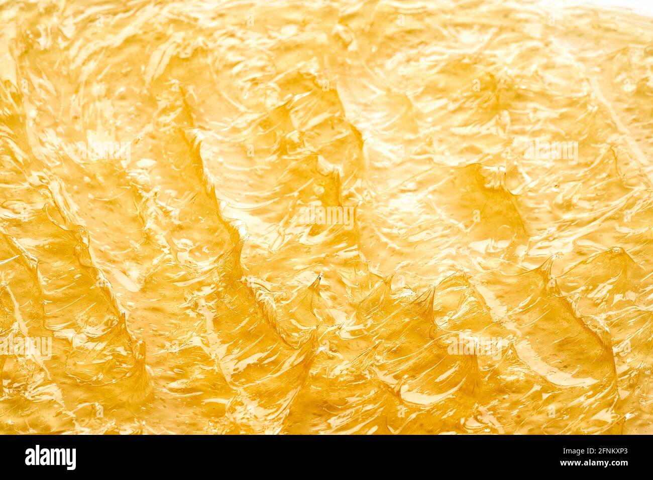 Transparenter gelber Abstrich von Gesichtscreme oder goldenem Honig isoliert auf weißem Hintergrund. Goldene cremige Textur auf weißem Hintergrund. Stockfoto