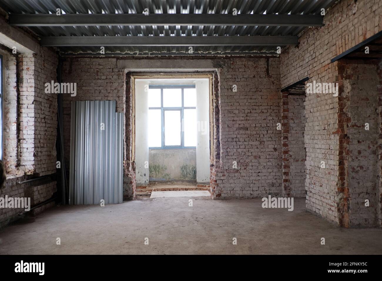 Das Innere des schäbigen Zimmers mit verwitterten Ziegelwänden war verödet Gebäude tagsüber Stockfoto