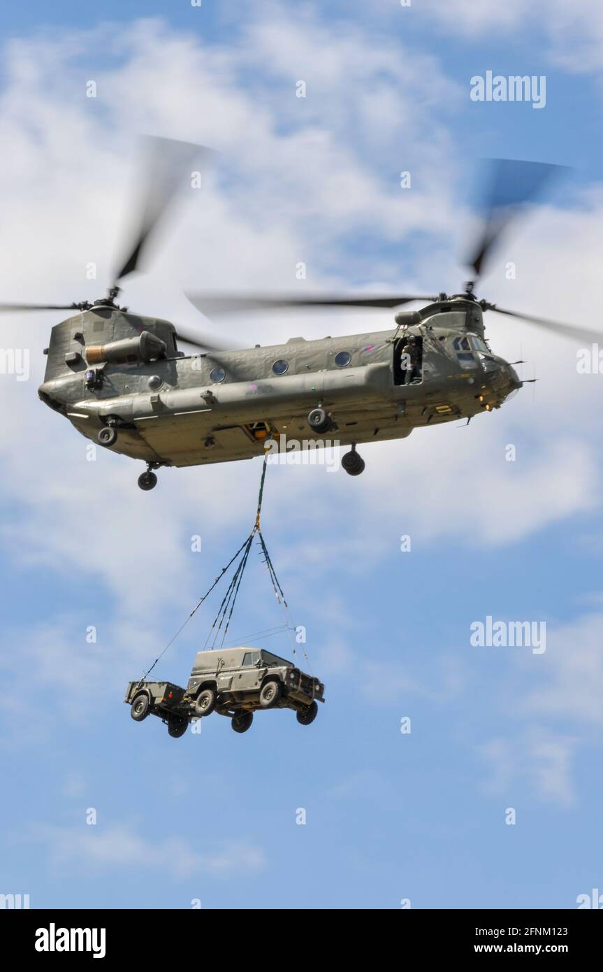 Royal Air Force, RAF, Boeing CH-47 Chinook Mittelhubschrauber mit einer Unterladung Land Rover Autos und Anhänger auf der Farnborough Airshow, Großbritannien Stockfoto