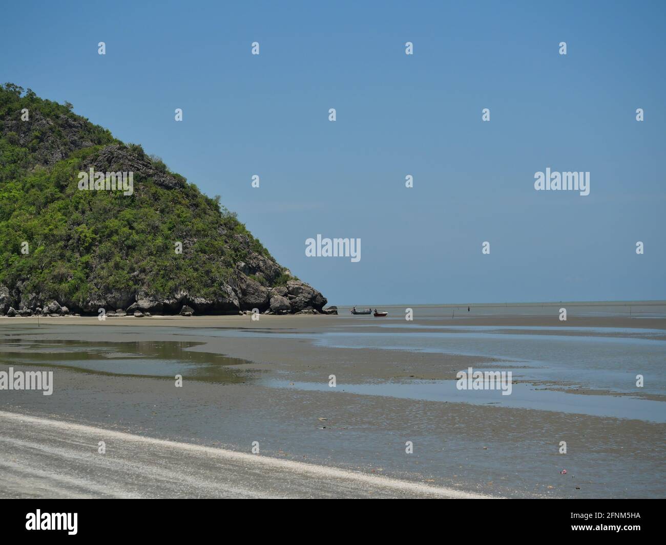 Berg mit Sand und Schlamm im Wasser Phänomen bei Ebbe, Fischerboot am Strand , Ozeanwellen spritzen die Küste schwer , Thailand Stockfoto