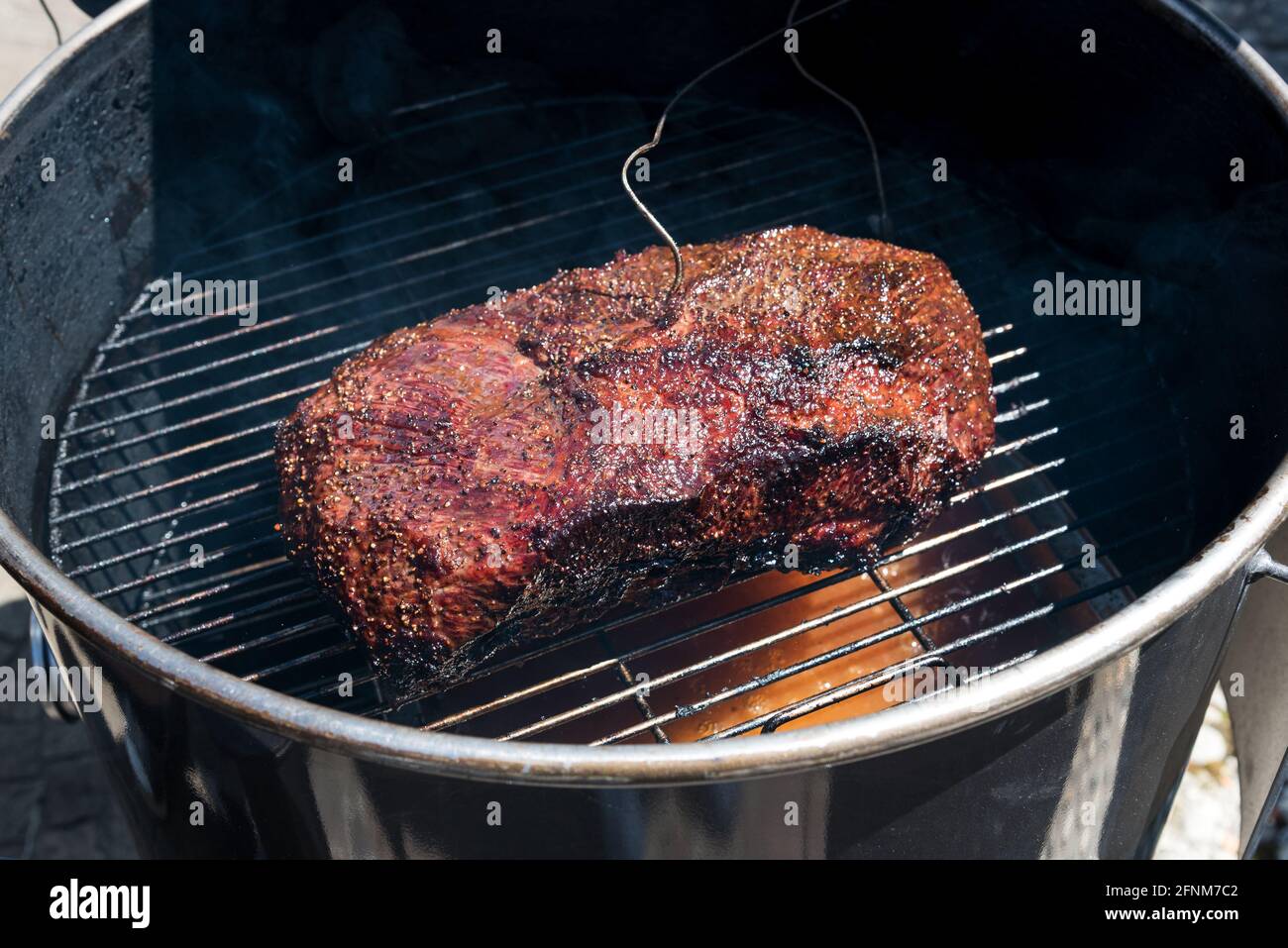 Thermometerdraht in einer Portion scharfer Rinderbrust Braten in einem Metall-BBQ oder Bräter in einem High-Angle-Ansicht Stockfoto