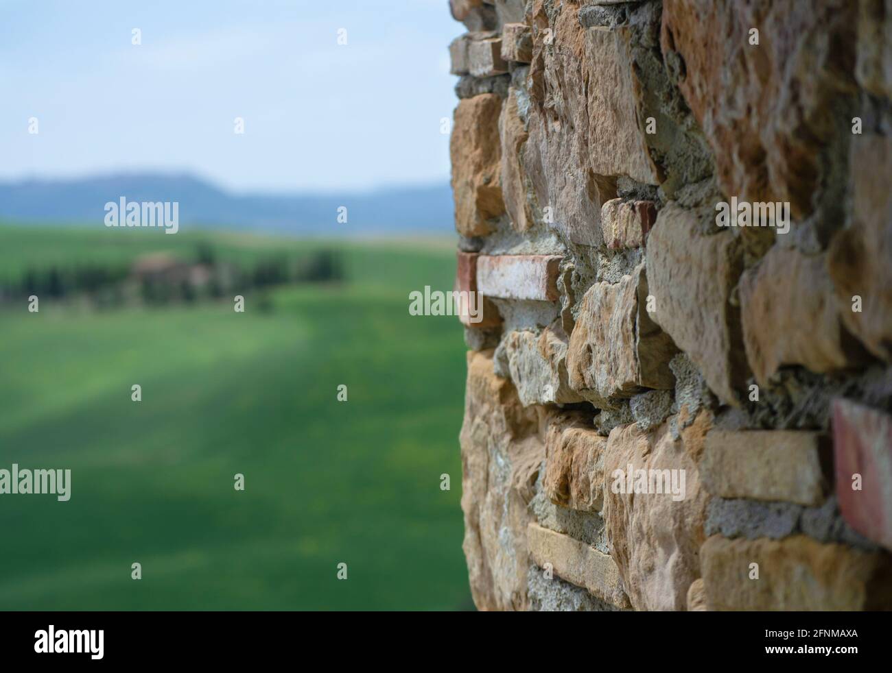 Textur einer Steinwand. Teil einer Steinmauer für Hintergrund oder Textur mit toskanischen Hügeln auf unscharfen Hintergrund Stockfoto