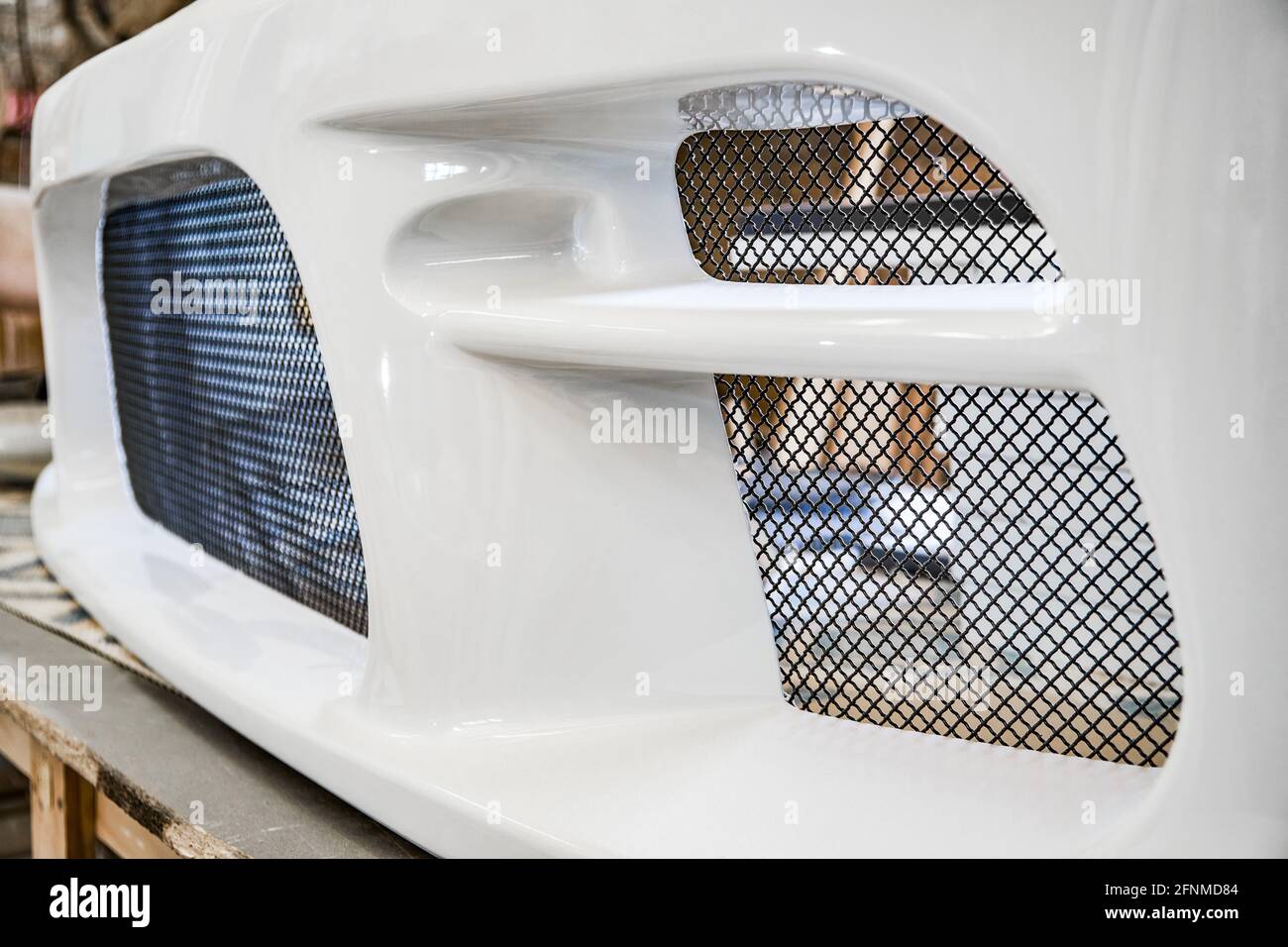 Dünnes Metallgitter auf weißem glänzenden Stoßfänger von zeitgenössischen installiert Automobil in Auto Tuning Station extreme Nahsicht Stockfoto