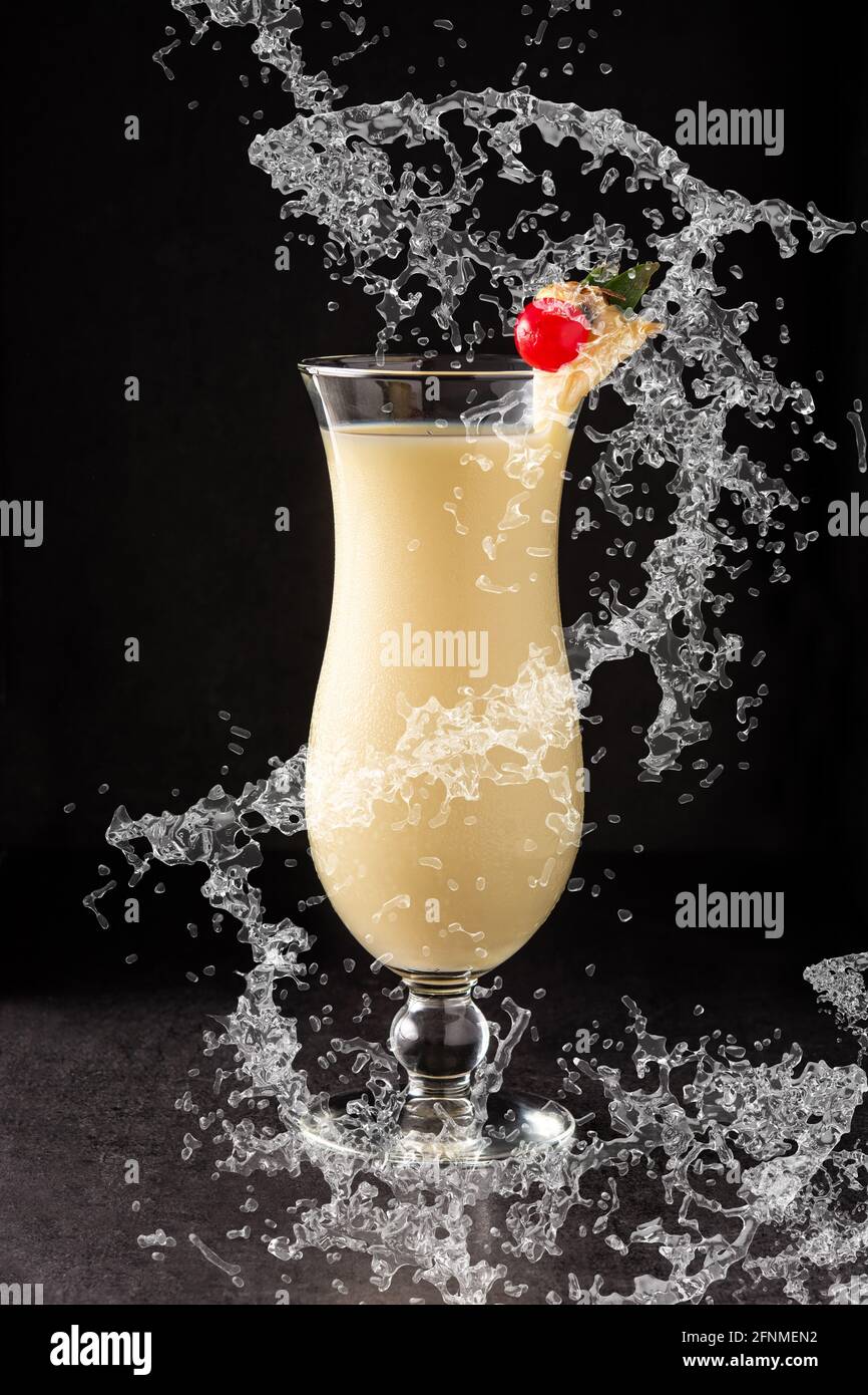 Pina Colada Cocktail spritzt in Glas auf schwarzem Hintergrund Stockfoto