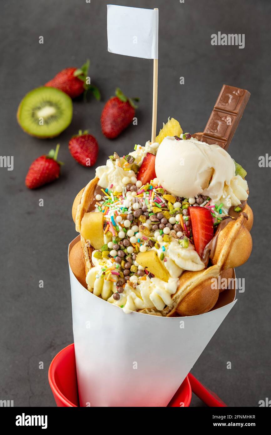 Hong kong oder Bubble Waffel mit Eis, Obst, Schokoladensauce und bunten Süßigkeiten Stockfoto