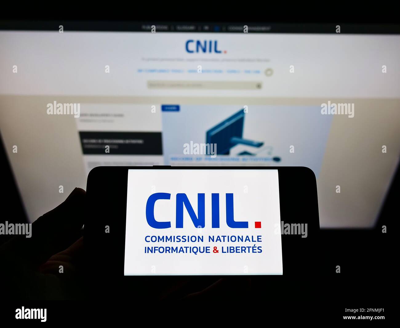 Person, die ein Mobiltelefon mit dem Logo der französischen Datenschutzbehörde CNIL auf dem Bildschirm vor der Webseite hält. Konzentrieren Sie sich auf die Anzeige des Mobiltelefons. Stockfoto
