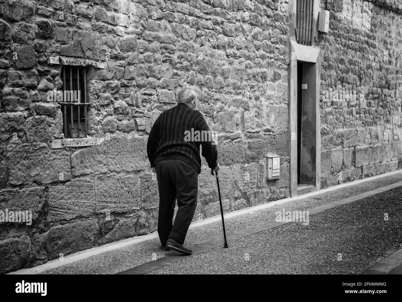 Älterer Mann mit Gehstock, der die Straße entlang läuft, aktiver Ruhestand, Lebensstil Stockfoto