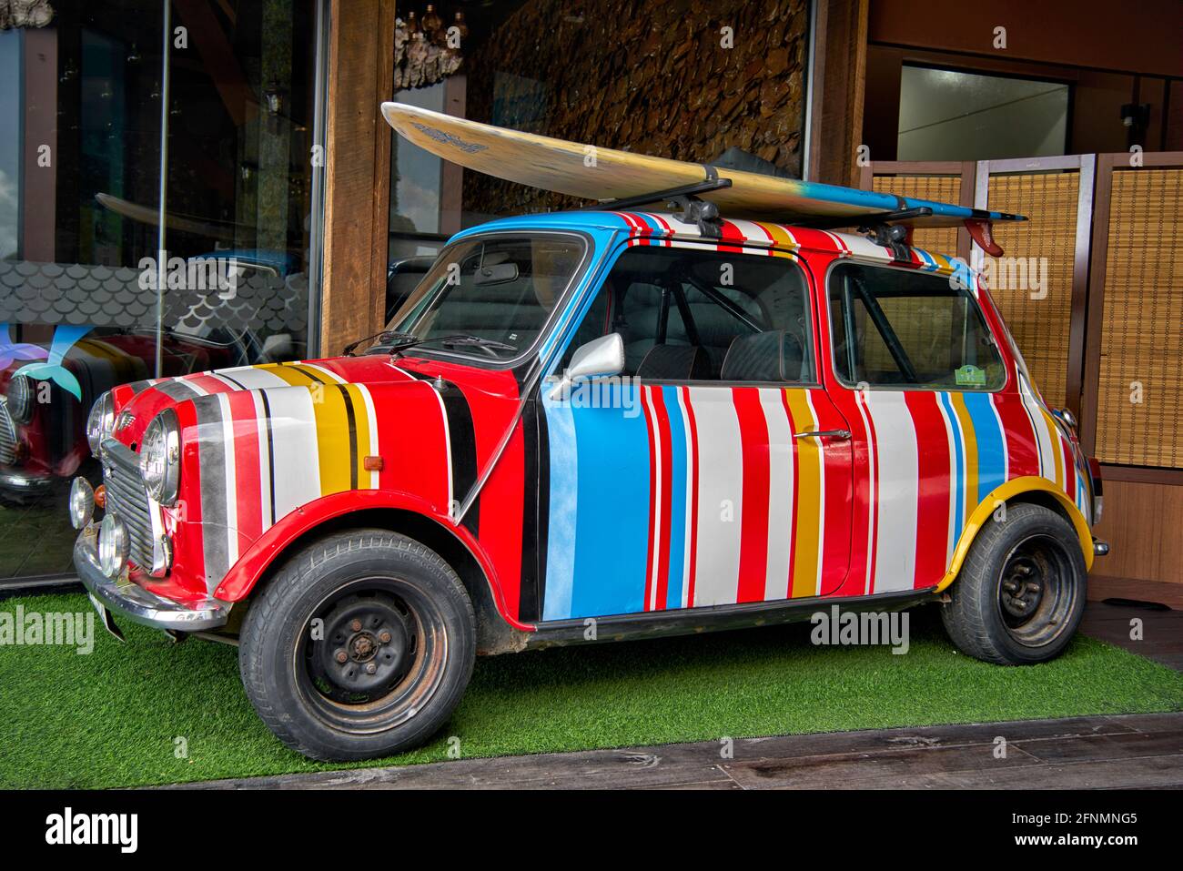 Paul Smith gestreifte Mini-Auto mit bunten Streifen mit Dach montiert Surfbrett lackiert. Fun Auto für junge Outdoor-Besitzer. Stockfoto