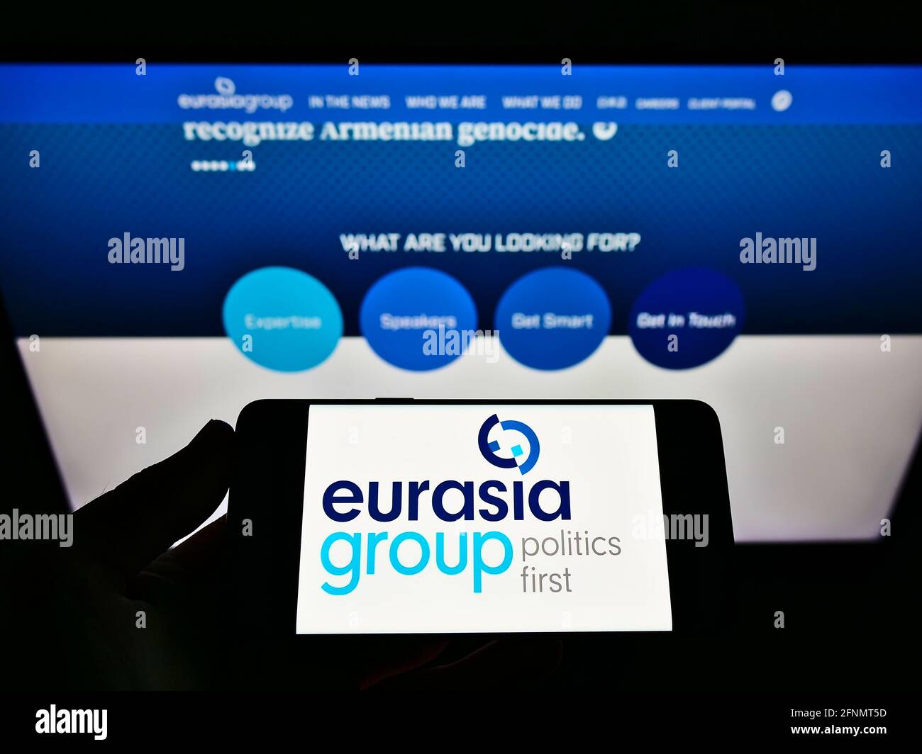 Person, die das Smartphone mit dem Logo der amerikanischen Beratungsfirma Eurasia Group Ltd auf dem Bildschirm vor der Website hält. Konzentrieren Sie sich auf die Telefonanzeige. Stockfoto