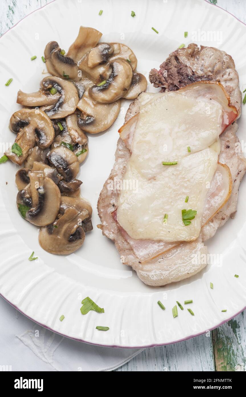 Vertikale Aufnahme von Schweinekoteletts mit Speck, Käse, Knoblauch, Pilzen Stockfoto