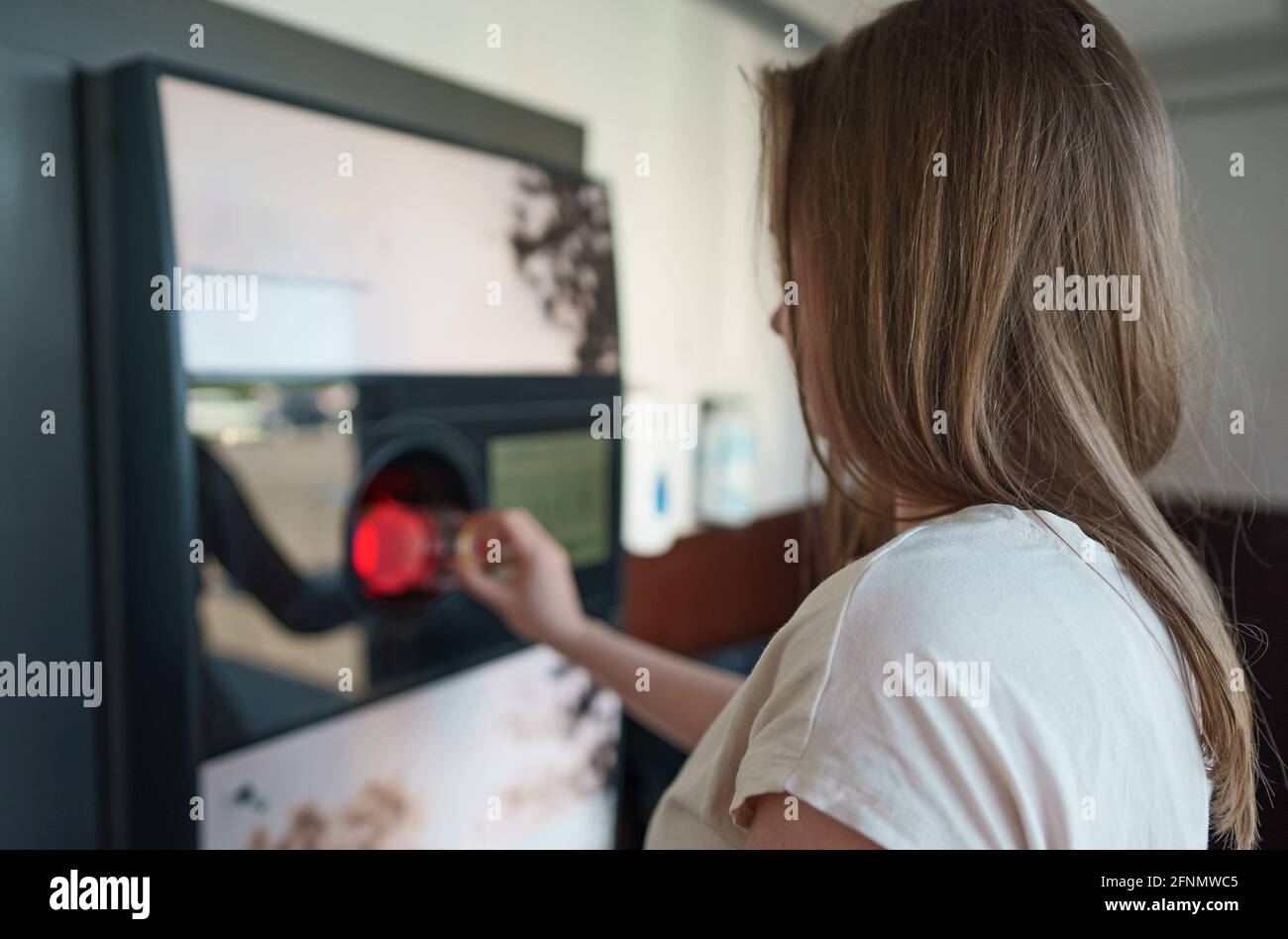 Frau stellt Flasche in automatische Flasche Recycling-Maschine. Recyclingautomat für Rückverkaufsautomaten. Stockfoto