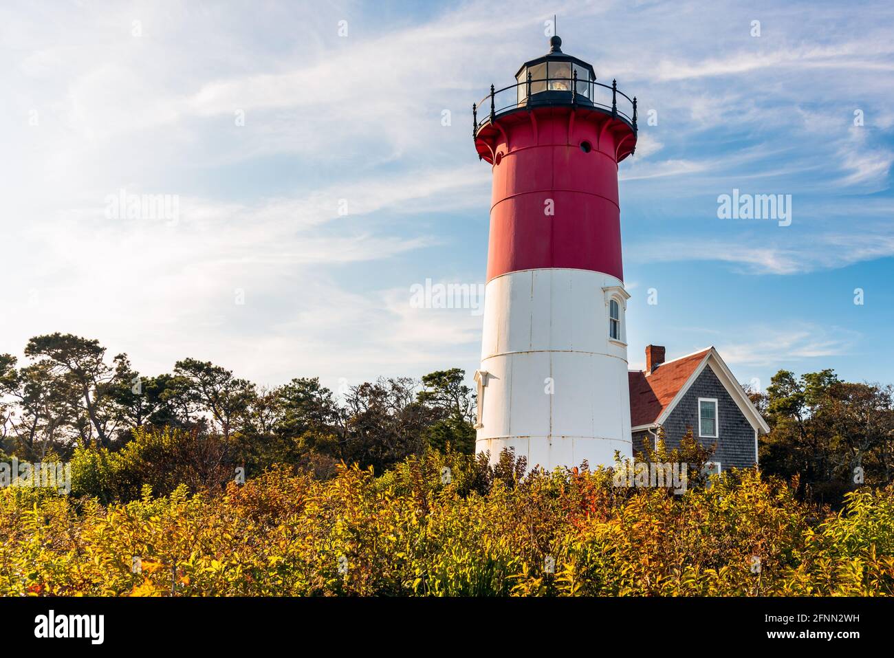 Historischer weißer und roter Leuchtturm unter bewölktem Himmel mit blauen Flecken bei Sonnenuntergang. Leuchtturm Nauset, Cape Cod National Seashore. Stockfoto