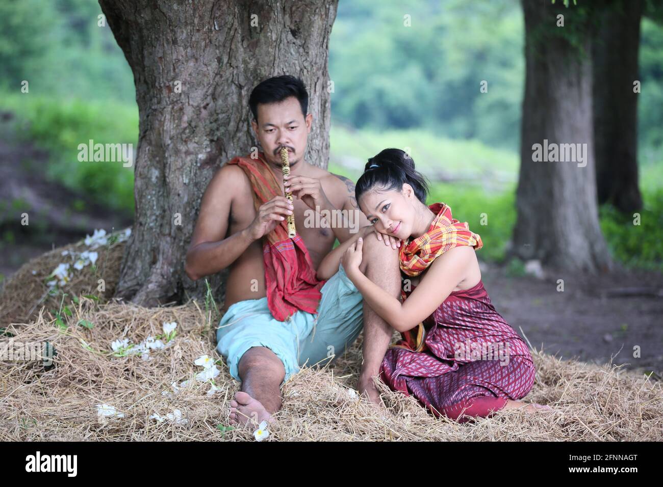 Liebe zum Asiaten Junge Männer und Frauen sitzen unter Bäumen gegen Büffel und natürlichen Hintergrund, ländliche Lebensweise im Nordosten Thailands. A Stockfoto