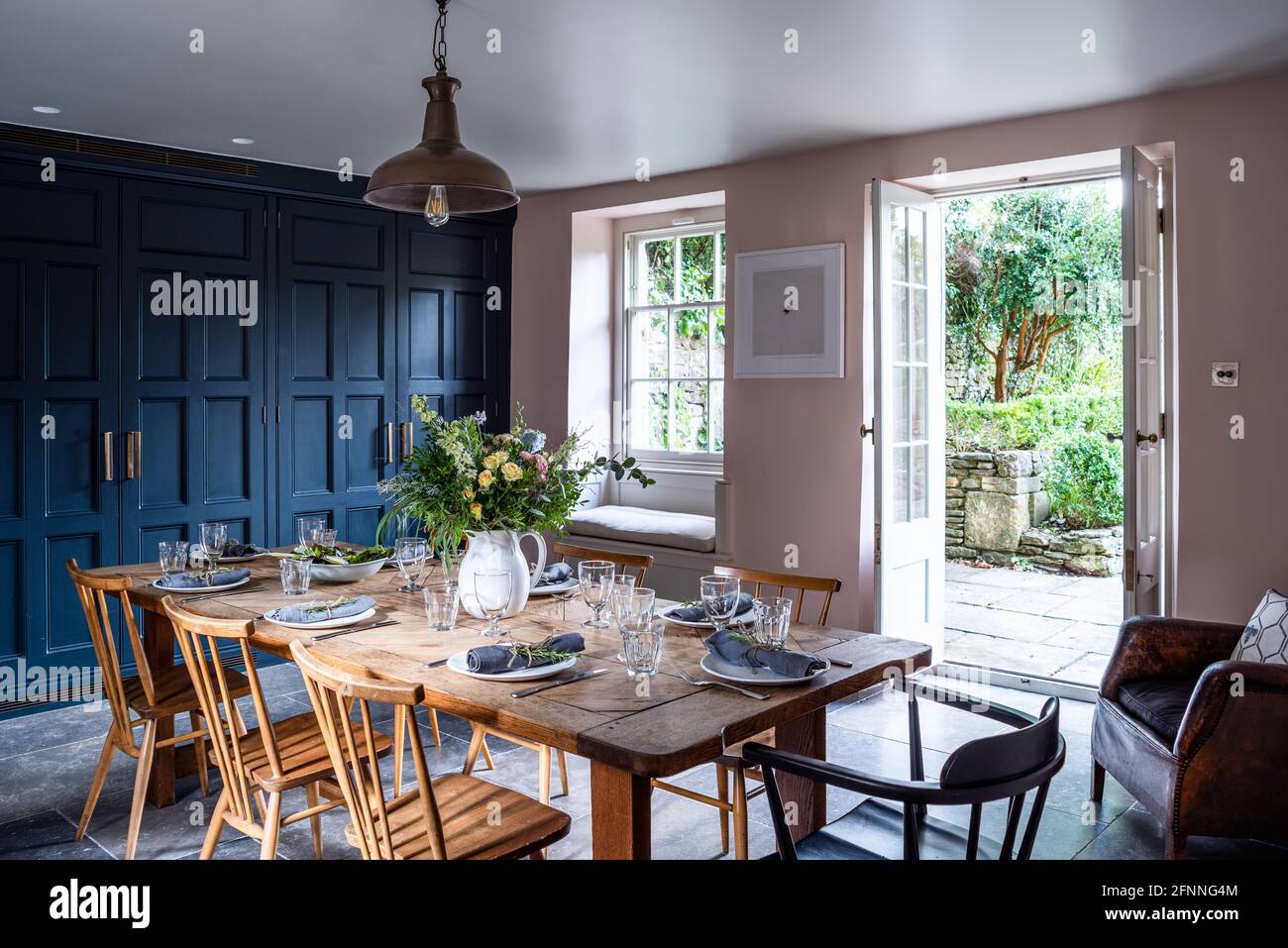 Esszimmer mit Schränken in Geländer und Wände in rosa Boden und offen für Garten, Somerset. Stockfoto