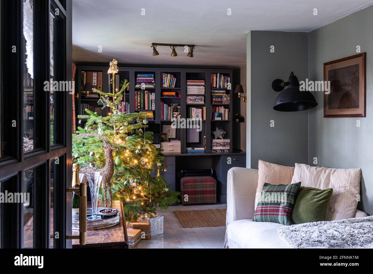 Bücherregal und Weihnachtsbaum mit Sofa in georgianischer Hütte, West Sussex. Stockfoto