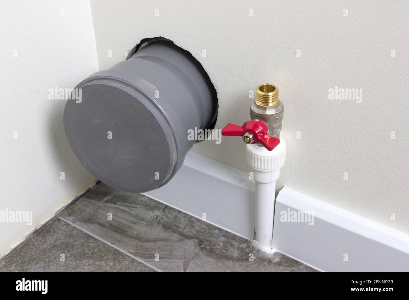 Abwasserleitung und Wasserzuleitung zum Toilettentank In der Ecke des Badezimmers Stockfoto