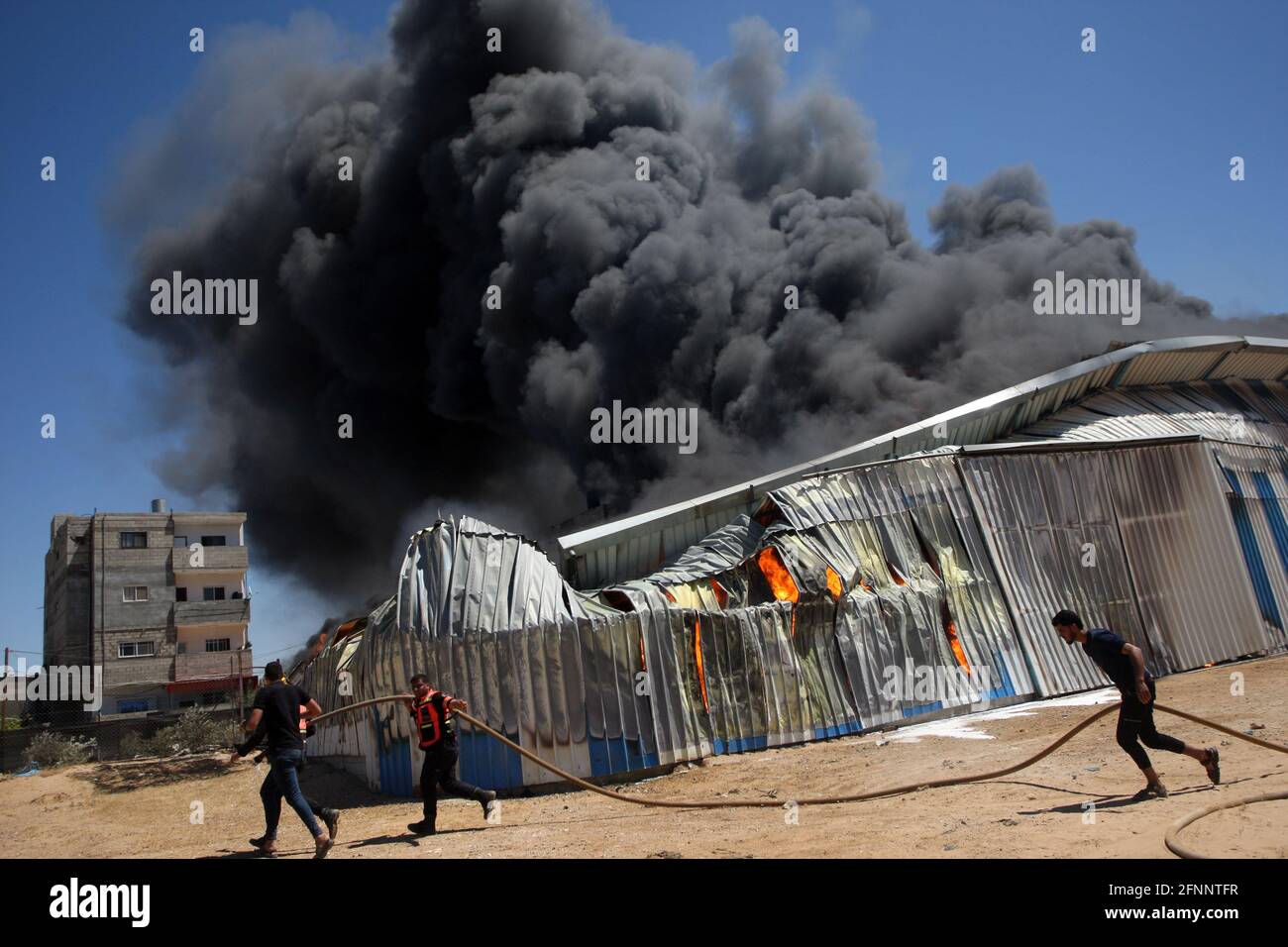 Am Dienstag, den 18. Mai 2021, löschen Menschen und Mitglieder der palästinensischen Zivilverteidigung ein Feuer in einem Farblager, das von einer israelischen Artilleriebülle auf dem östlichen Rafah im südlichen Gazastreifen getroffen wurde. Foto von Ismael Mohamad/UPI Stockfoto