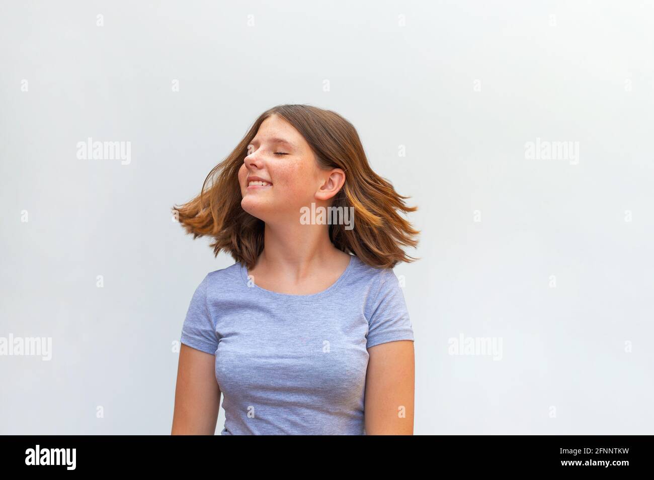 Portrait von schönen kaukasischen Teenager-Mädchen mit fliegenden Haaren lächelnd Lachen Entspannen Sie sich auf weißem Hintergrund Stockfoto