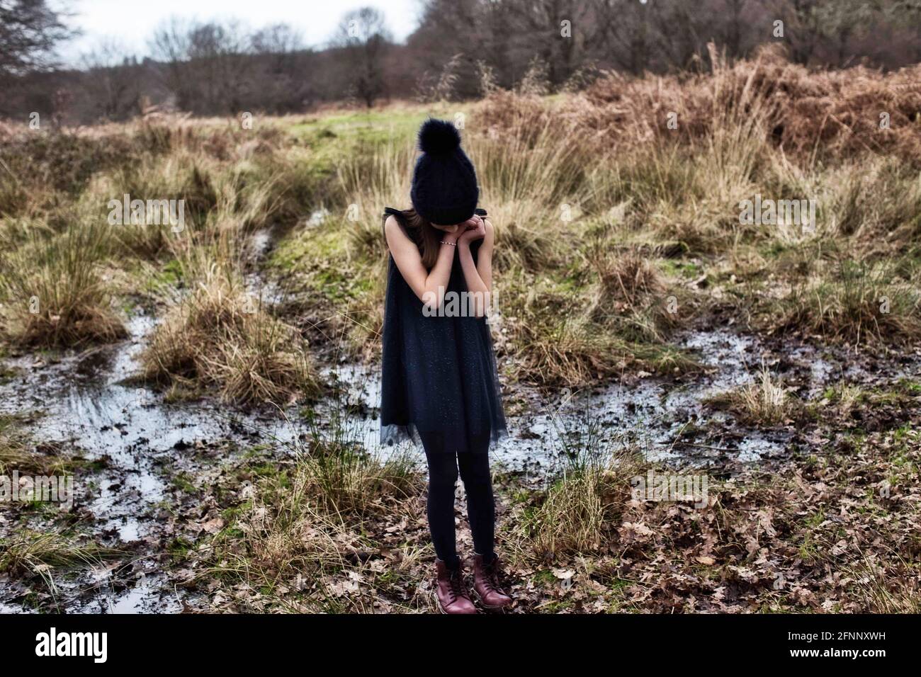 Ein kleines Mädchen, das in einer unheimlichen, gruseligen Landschaft steht. Mädchen, das auf einem Moor steht Stockfoto