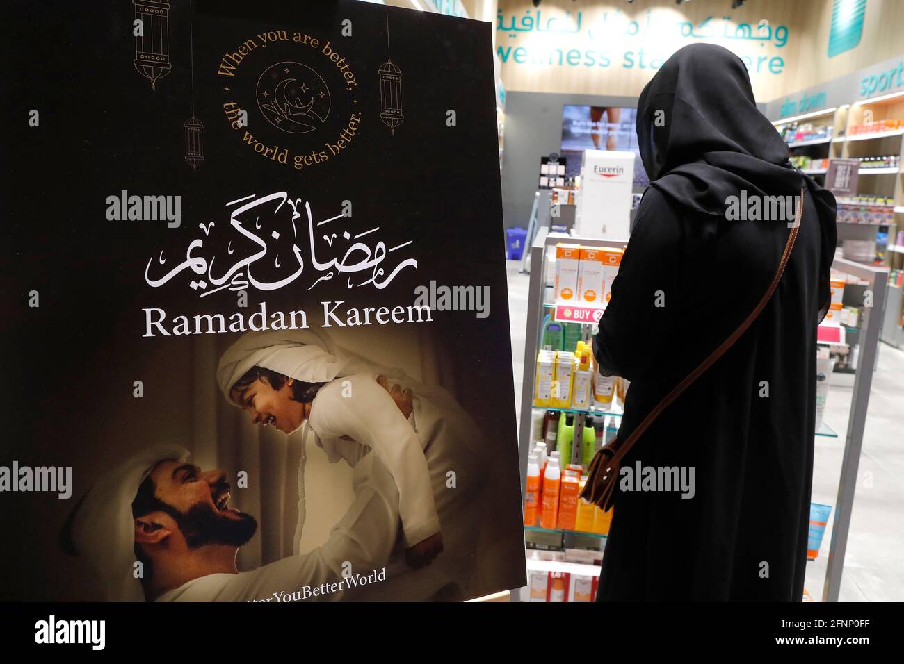Ramadan kareem arabische Kalligraphie Gruß mit Halbmond und Laternen. Muslimische Frau mit Abaya im Geschäft. Dubai. Vereinigte Arabische Emirate Stockfoto
