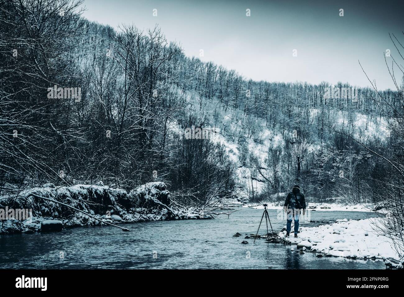 Mann Fotograf am Flussufer an einem Wintertag Stockfoto