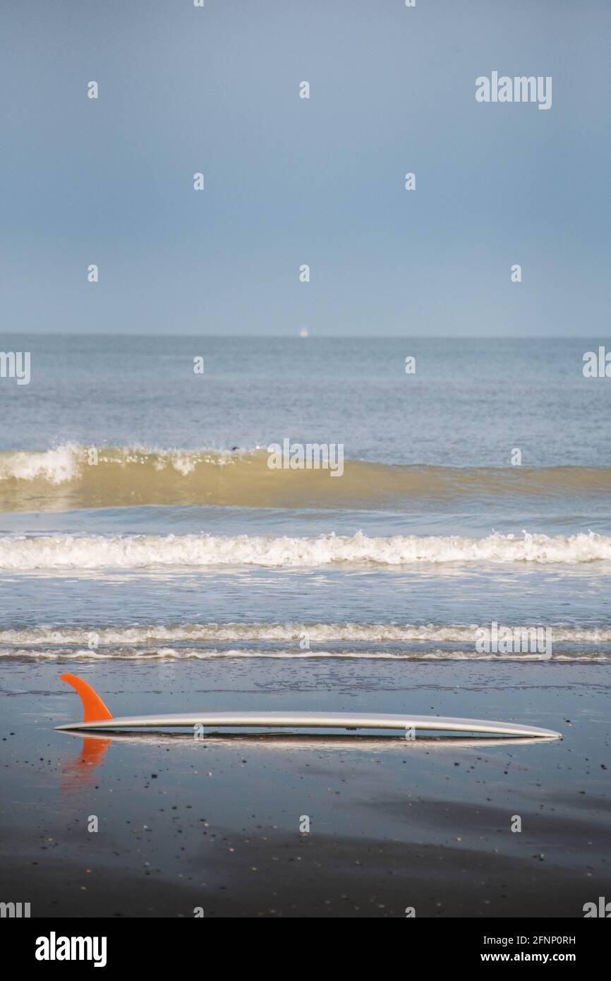 Am Strand liegt ein Surfbrett mit oranger Flosse Stockfoto
