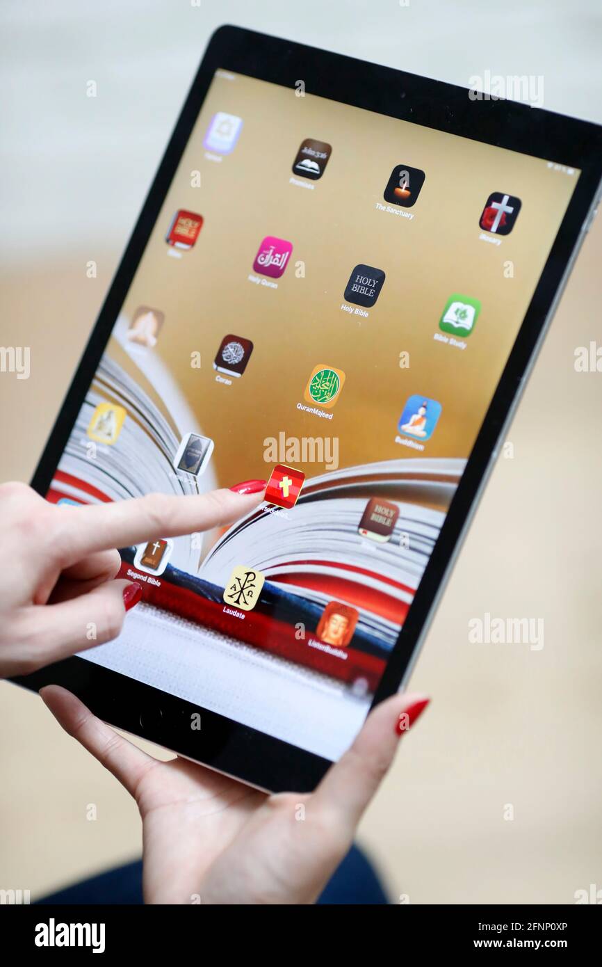 Frau liest ein digitales Tablet iPad mit verschiedenen religiösen digitalen Apps. Christentum, Islam, Judentum, Buddhismus. Interreligiöse Symbole. Frankreich. Stockfoto