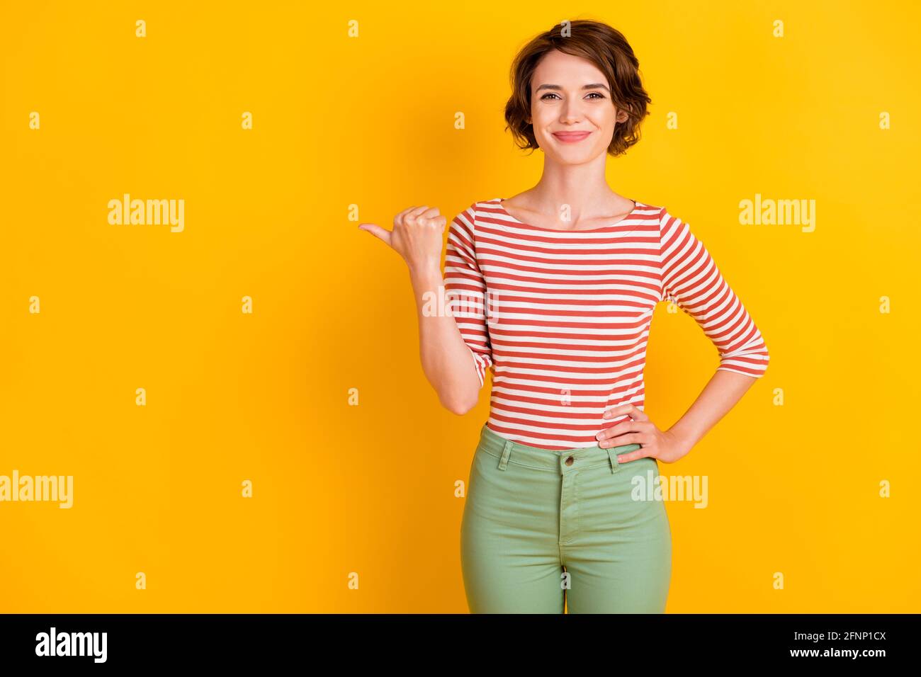 Portrait Foto von Mädchen mit bob Haar zeigt auf leer Space lächelnd isoliert auf lebhaft gelben Hintergrund Stockfoto