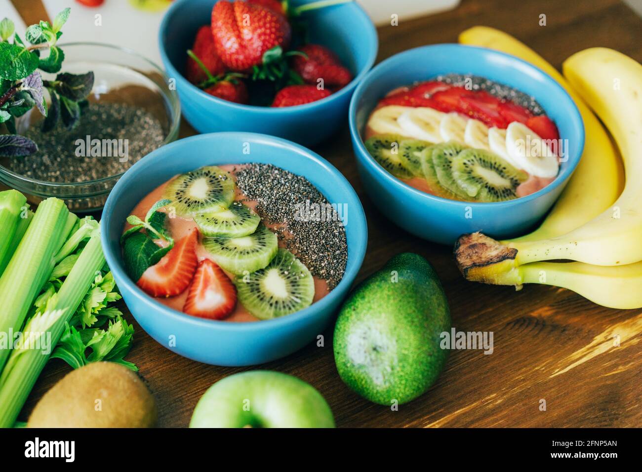 Auf dem Tisch stehen Tassen mit frischen, köstlichen Smoothies sowie Obst und Samen. Stockfoto
