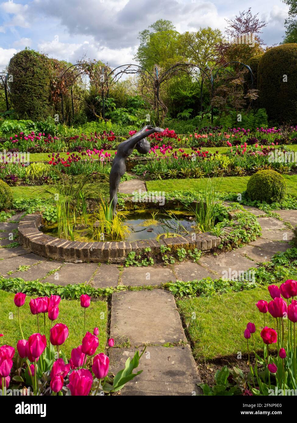 Chenies Manor Garden 2021, ovaler Zierteich im versunkenen Garten, Alan Biggs Skulptur, „The Tauche“ in der Mitte und farbenfrohe Tulpen und Rasenflächen Stockfoto