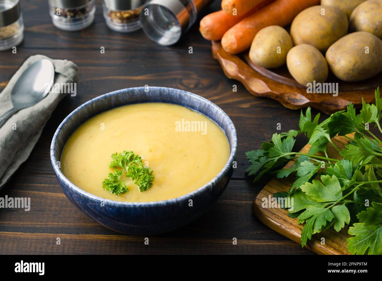 Frisch gekochte Kartoffelsuppe in einer Schüssel, garniert mit Petersilie Und Zutaten und Löffel herum Stockfoto