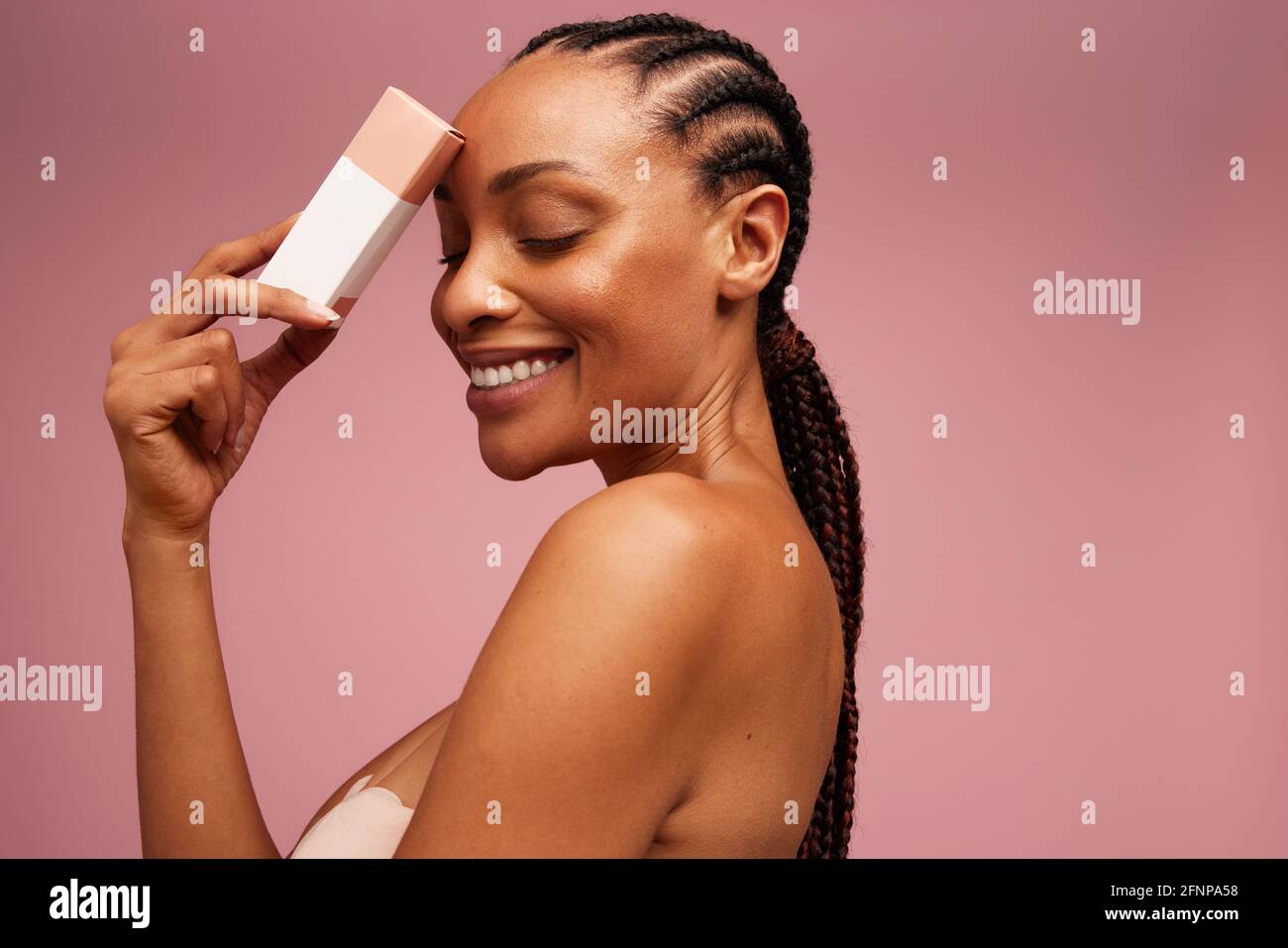 Hübsches Weibchen mit Beauty-Produkt. Frau lächelt mit geschlossenen Augen und hält ein kosmetisches Produkt. Stockfoto