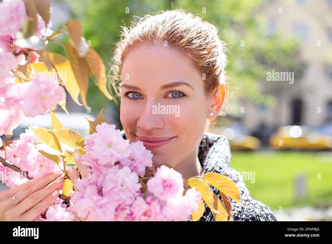 Glückliche junge fröhliche kaukasische Rotschopf Frau mit Kirschbaum Zweig Stockfoto