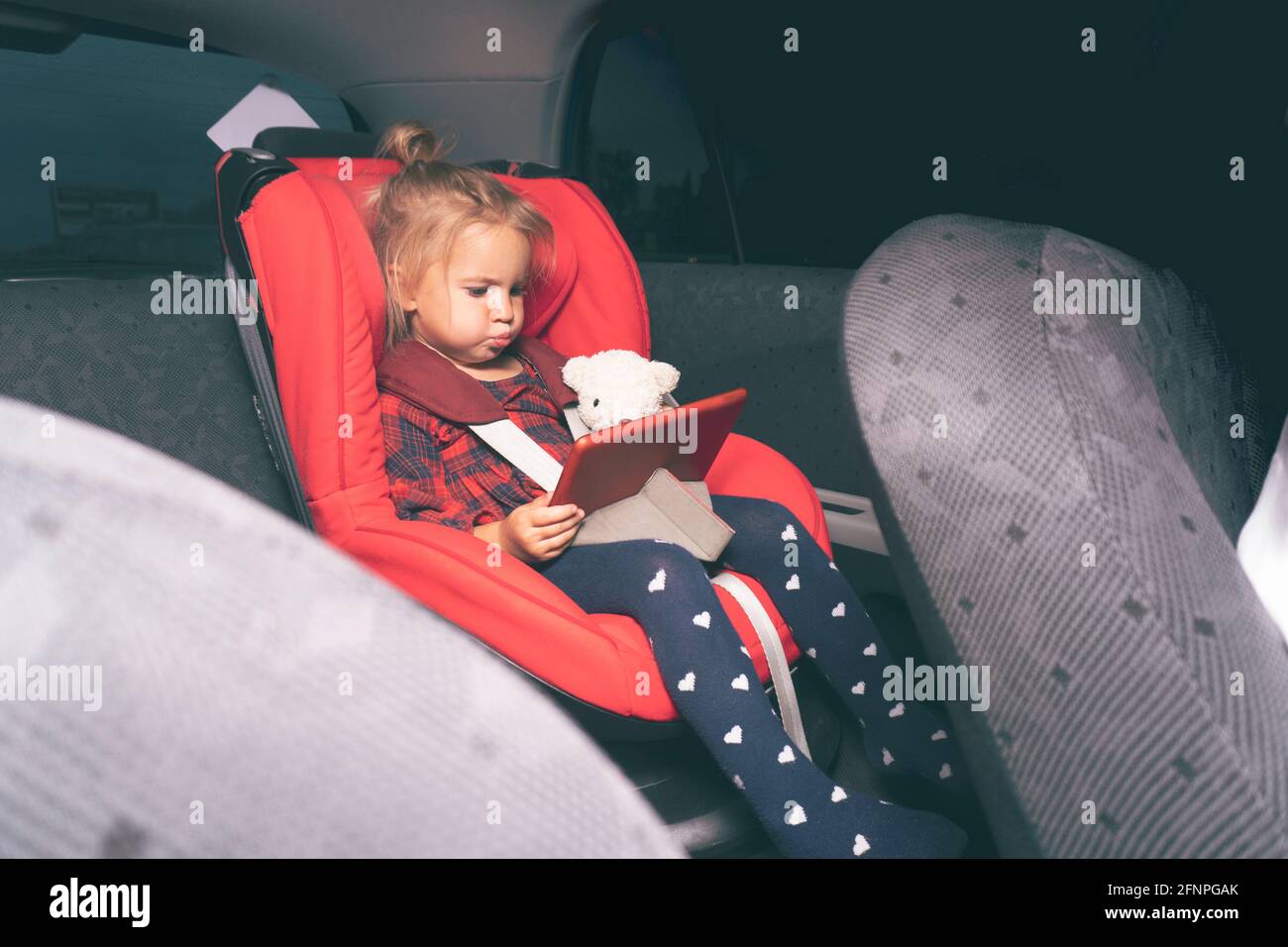 Niedliches kaukasisches kleines Kind, das am Sicherheitsautositz sitzt Kinder Stockfoto