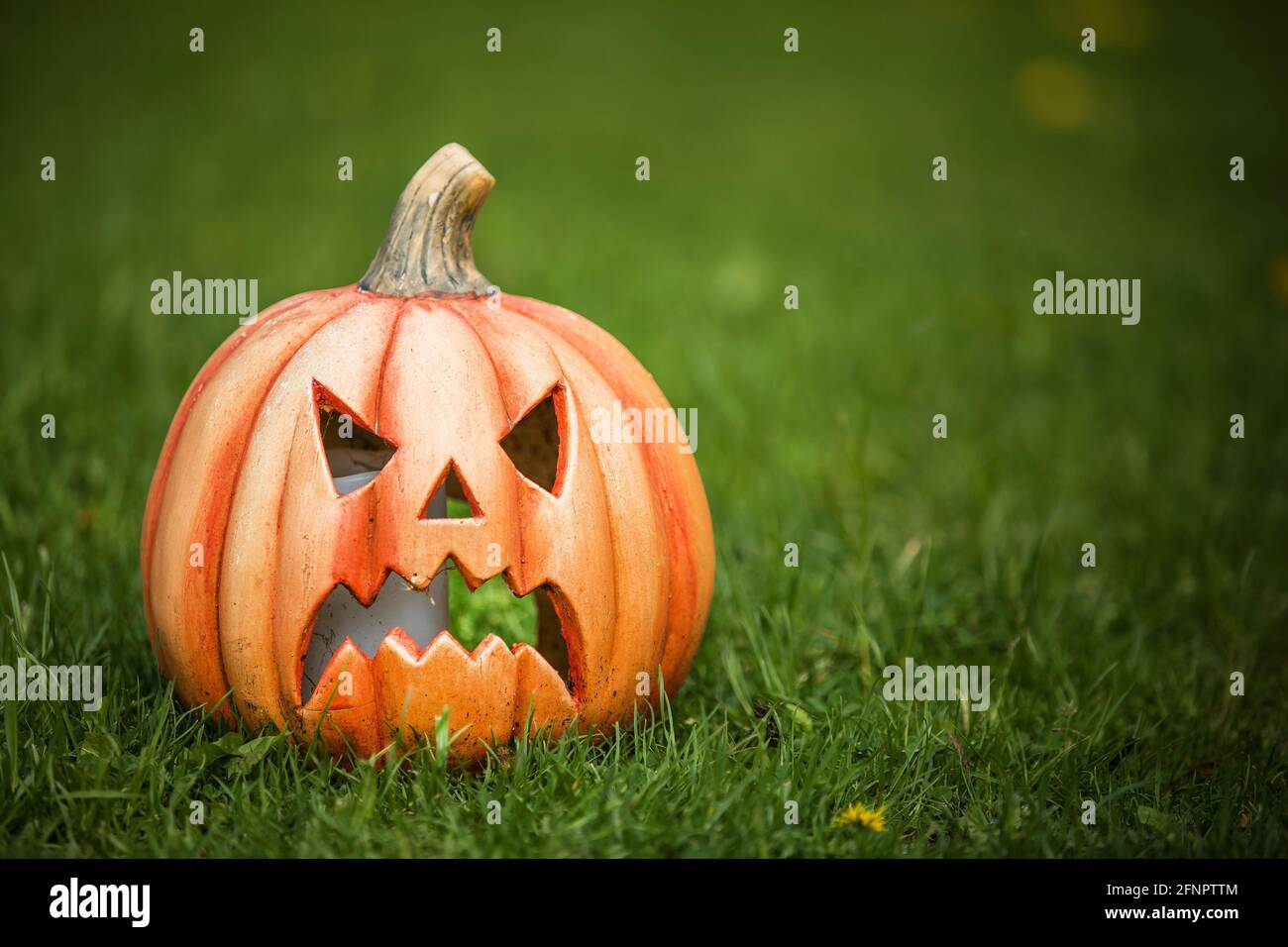 Kürbis geformter Keramik-Kerzenhalter auf grünem Gras. Lustige geschnitzte Kürbis im Garten, halloween-Hintergrund Stockfoto