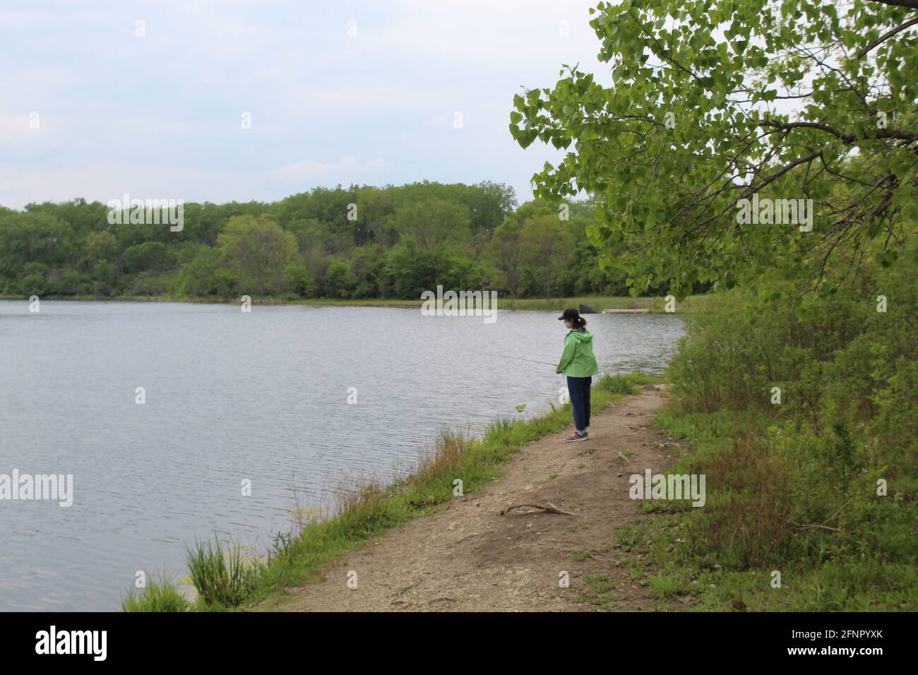 Frau mit einer PSA-Maske beim Fischen am Big Bend Lake in des Plaines, Illinois Stockfoto