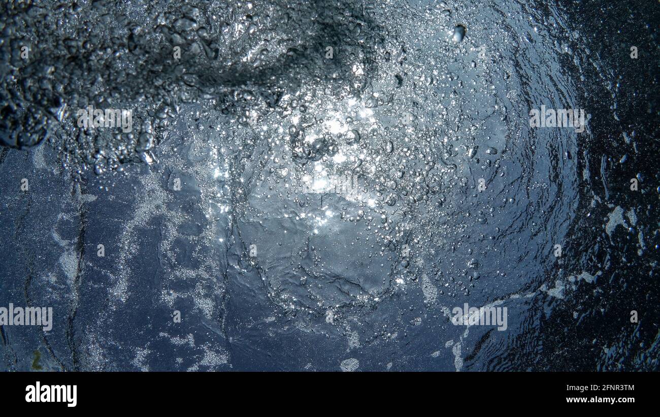 Foto schließen von vielen schönen Unterwasserluftblasen steigen durch blaues Meerwasser vom atmenden aufsteigenden Fahrer auf, Foto auffüllen. Das Sonnenlicht winkt Stockfoto