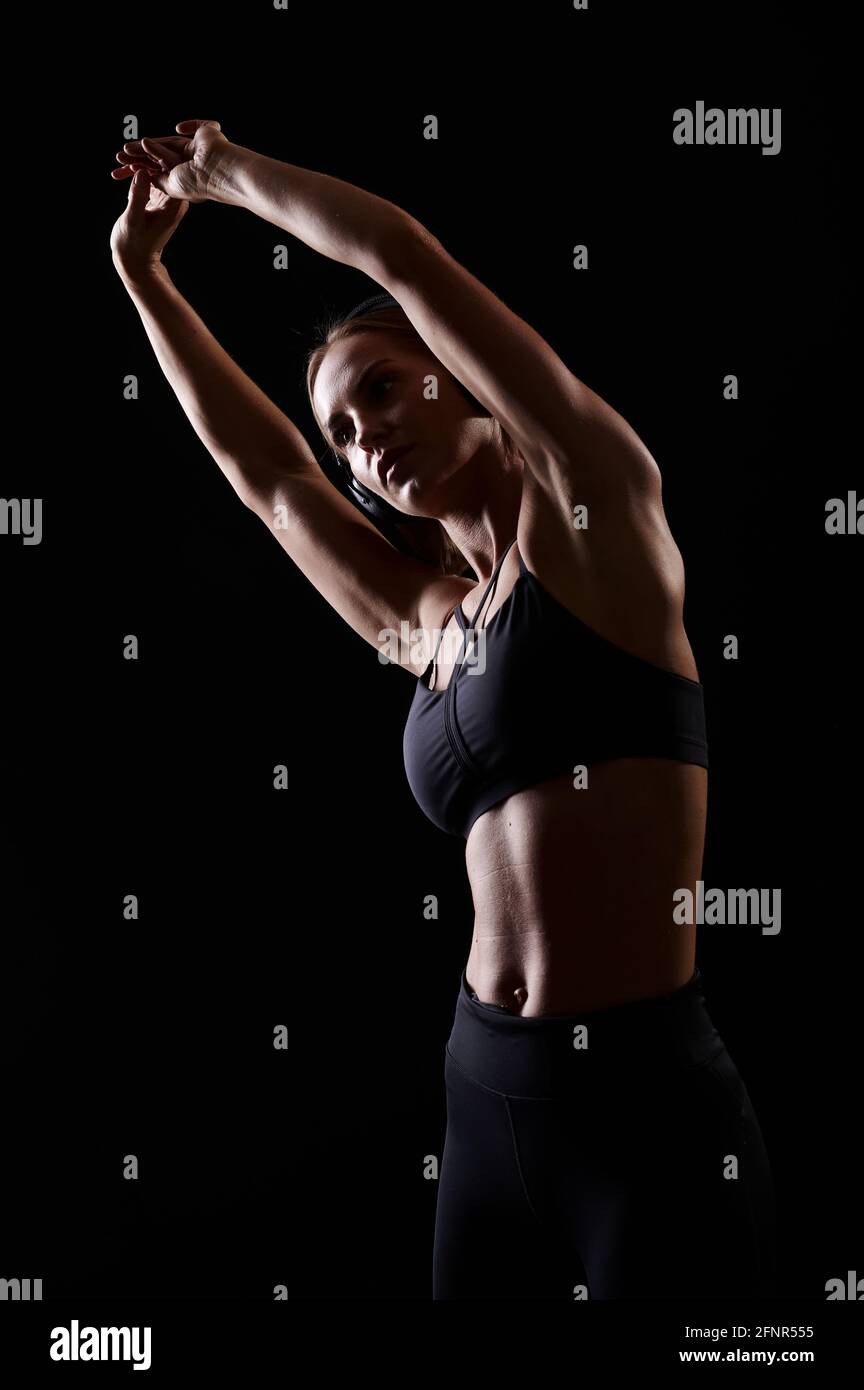 Schlanke, starke, muskulöse Sportlerin, die sich vor dem Training dehnt und Musik hört. Gesunder Lebensstil. Stockfoto