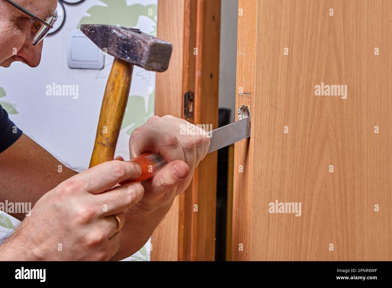 DIY Montage der Verriegelung in der Tür, Nut wird mit Meißel für die Schlossplatte ausgeschnitten. Stockfoto