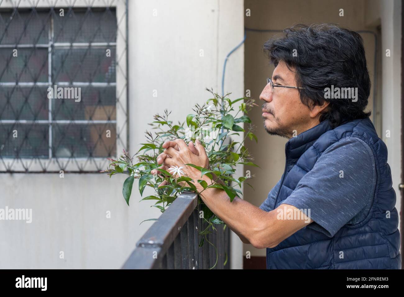 Hispanic-Mann, der vom Balkon aus schaute Stockfoto