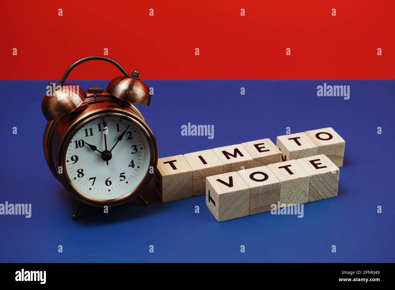 Zeit zum Abstimmen Alphabet Buchstaben mit Wecker auf blauem und rotem Hintergrund Stockfoto