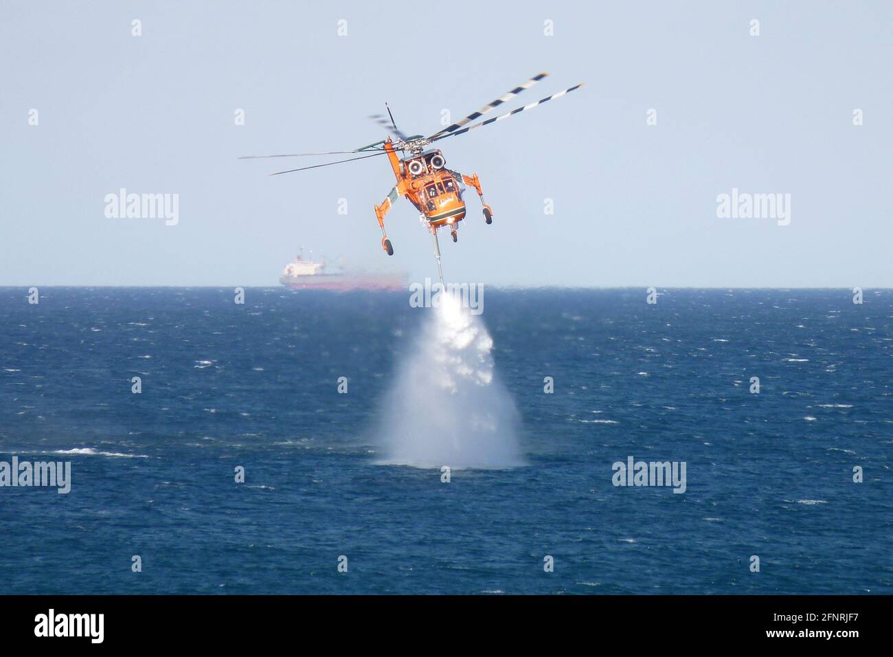 Der Erickson S64E Aircran hebt das Meerwasser durch seinen Schnorchelschlauch, um es auf einem nahegelegenen Buschfeuer in der Nähe des Lake Macquarie, NSW, Australien, einzusetzen Stockfoto